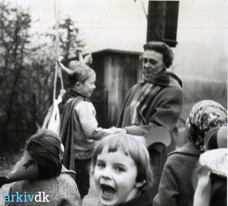 arkiv.dk | Foto af børnehaveleder ved Amtssygehusets Gunna Gunnersen, omgivet af otte udklædte børn til De har lige slået af tønden.